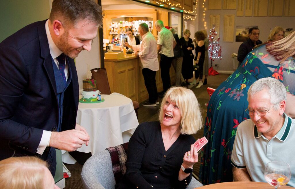 Guests seated at table enjoying magic at a Christmas party.