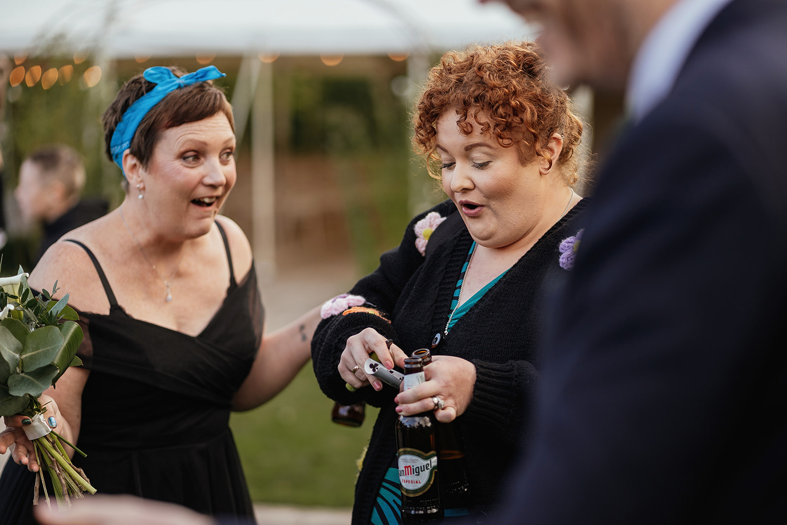 Two women laughing in shock while holding playing card during close up magic performance in Essex
