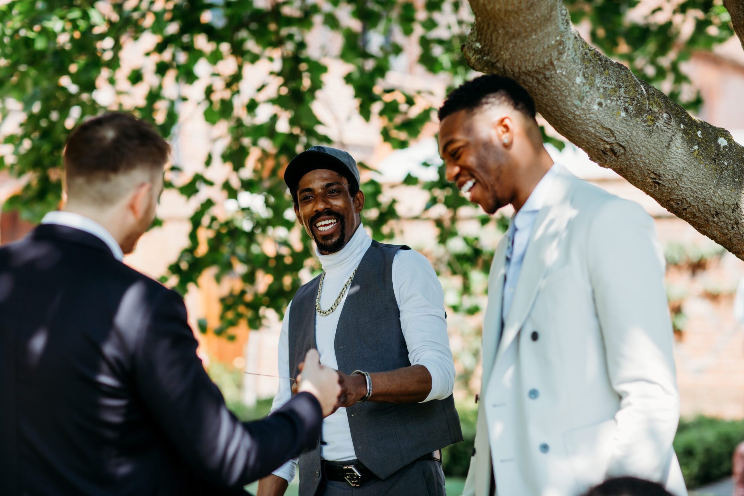 Close-up magician entertaining guests at an outdoor gathering, leaving two men amazed and suspicious after a fun magic trick