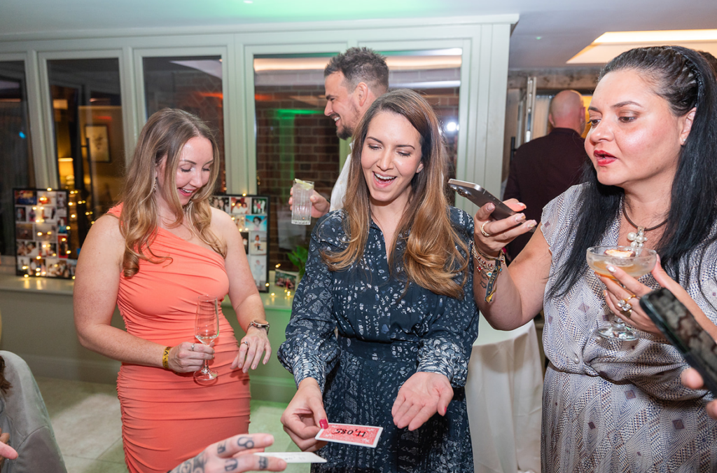Birthday girl laughing during close up magic performance at milestone celebration birthday party
