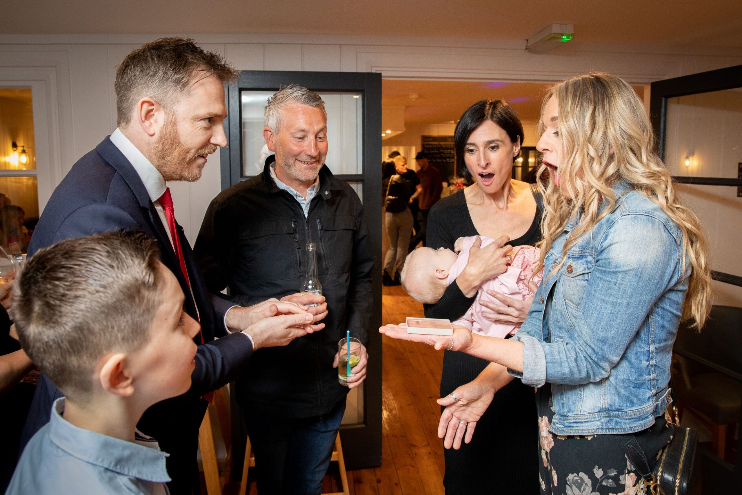 Group of guests reacting with surprise to a close up magic trick at a London birthday party