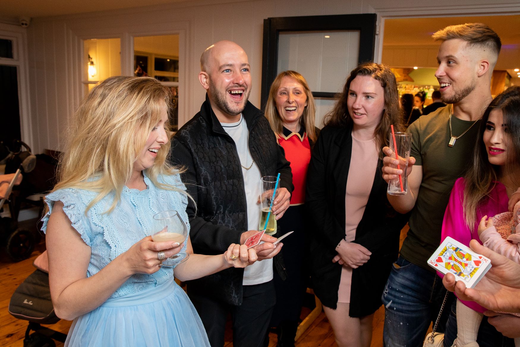 Young adults enjoying a magic trick at a milestone birthday party, birthday girl amazed
