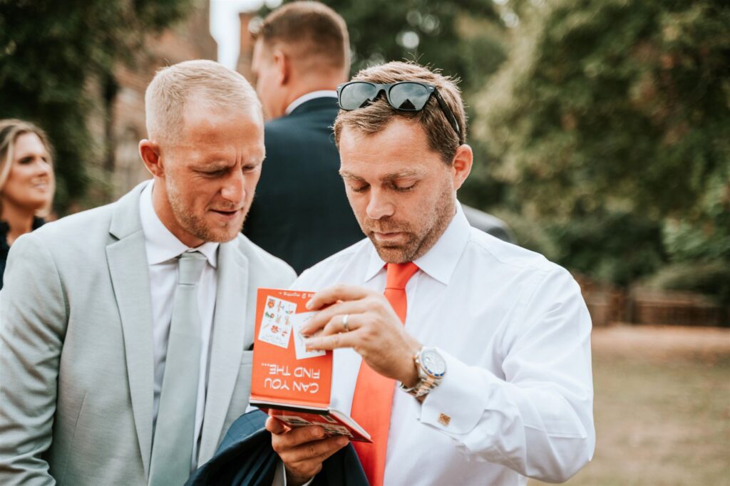 Two wedding guests reading a magic prop to start a close up trick during drinks reception