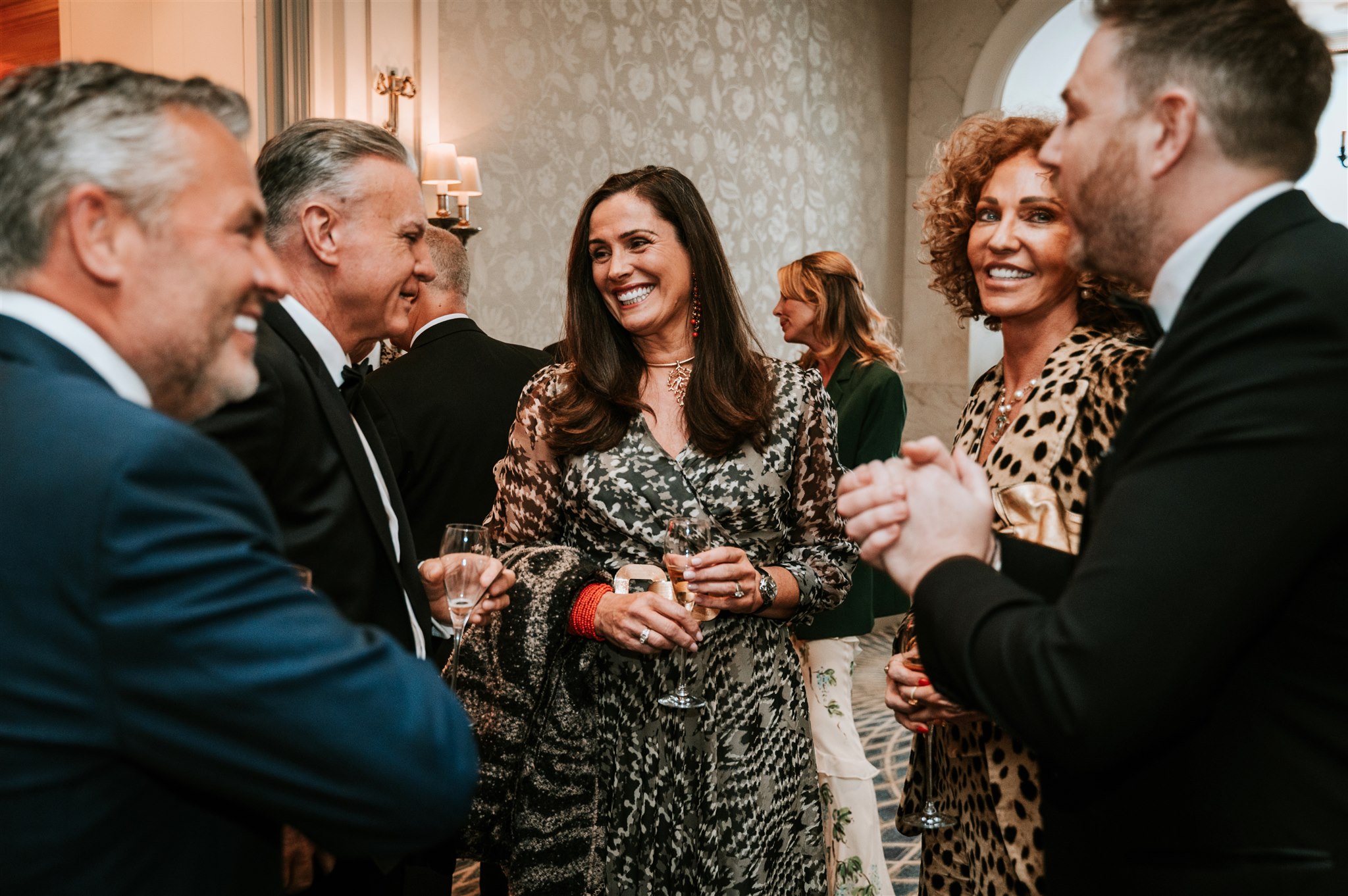 Guests smiling and interacting with a close-up magician during a 60th birthday celebration