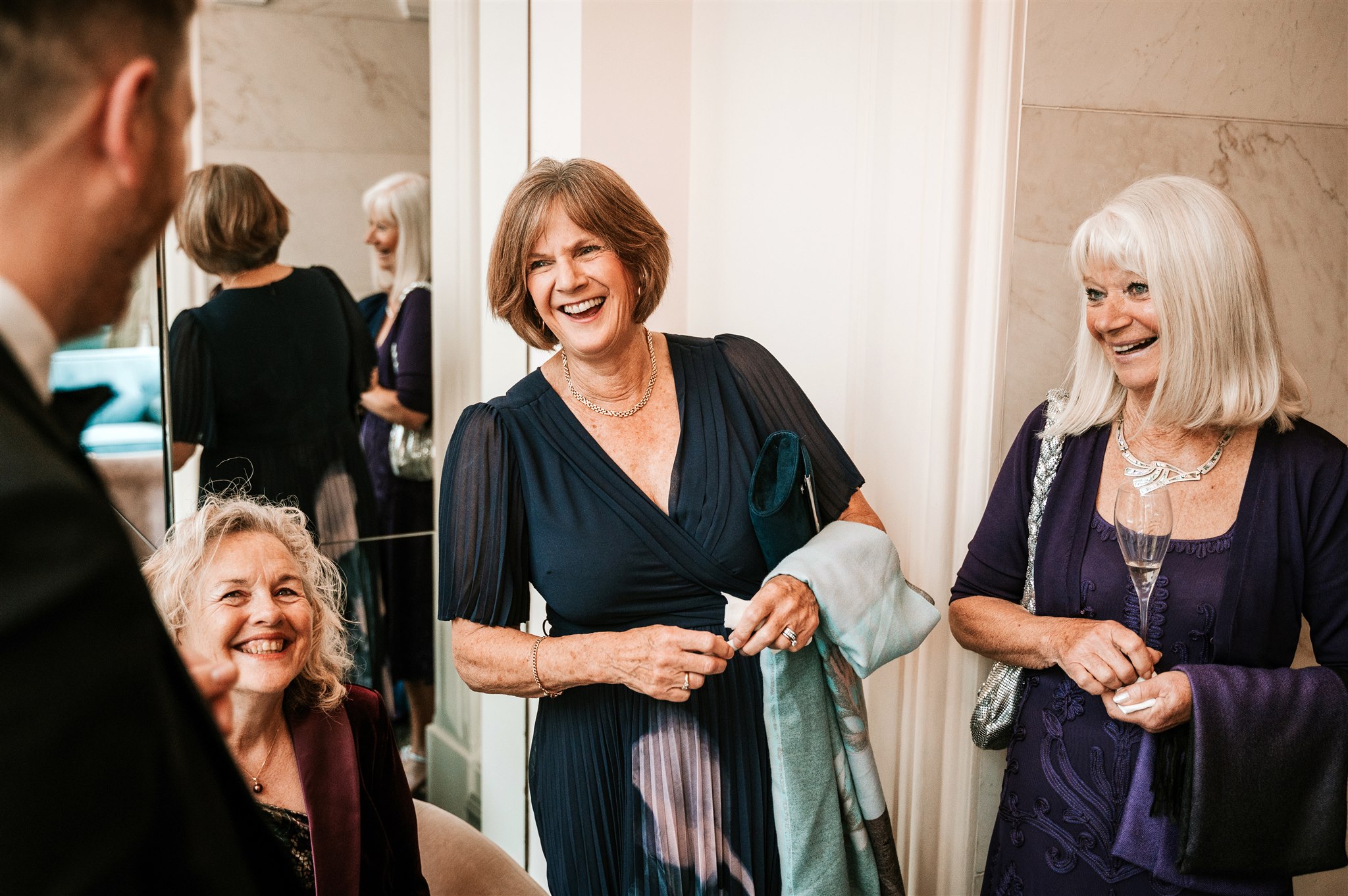 Women in their 50s and 60s laughing and reacting to close-up magic at a birthday party