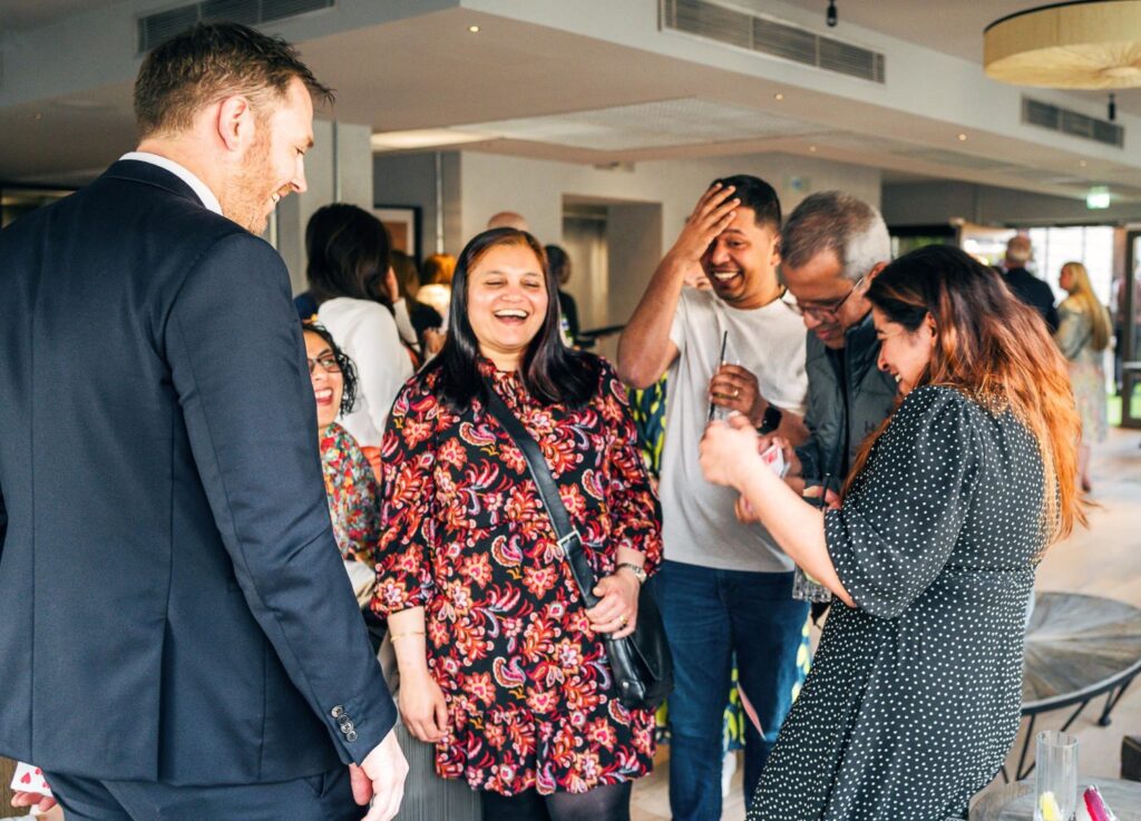 Group of guests interacting with magician at a Christmas event enjoying the magic trick.