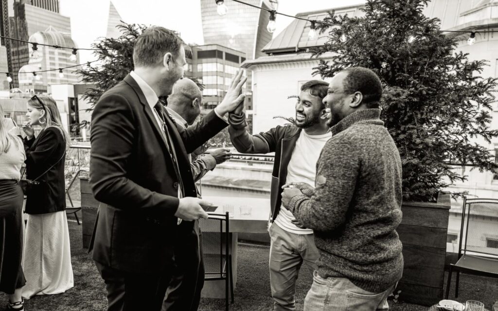 Guests high fiving a magician during a rooftop corporate Christmas party celebration