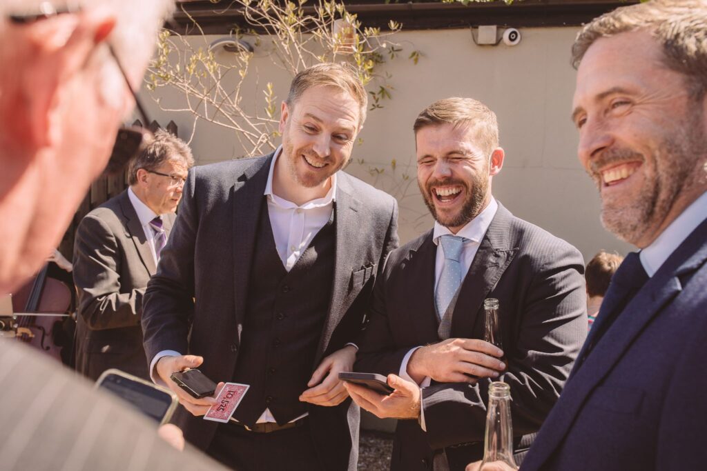 Smartly dressed guest in suit laughing during close up magic trick at birthday celebration
