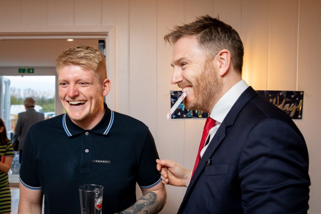 Guest laughing at card appearing in magician mouth reveal
