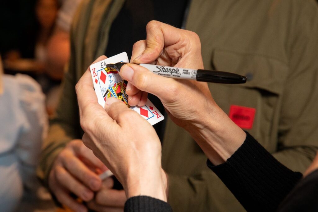 Guest signing playing card before magic trick begins
