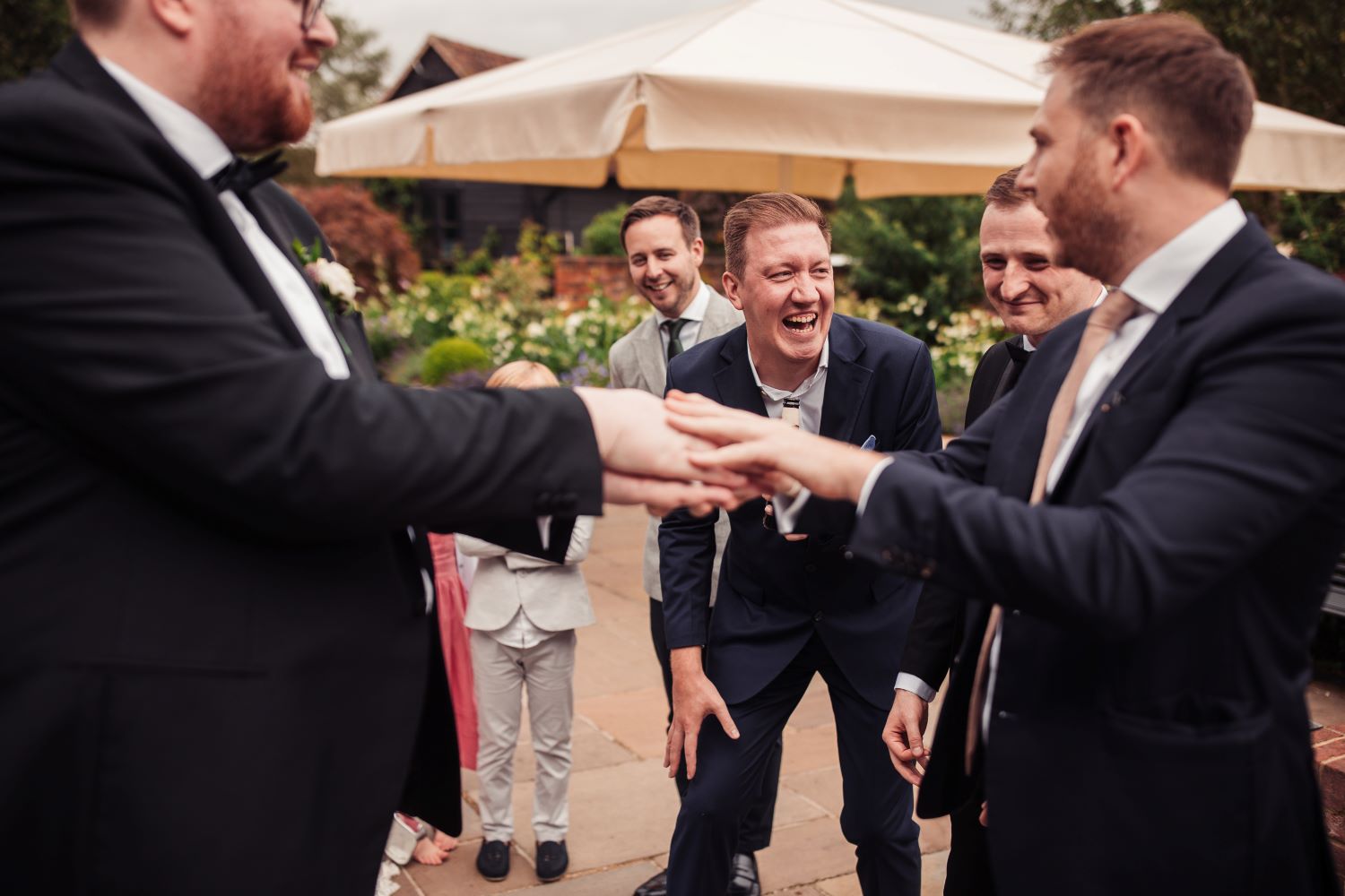 Groom and wedding guests laughing during close up magic performance