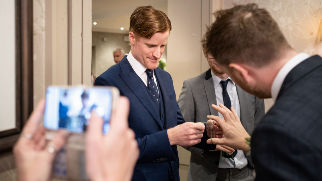 Wedding guest filming a close up magic trick during the reception