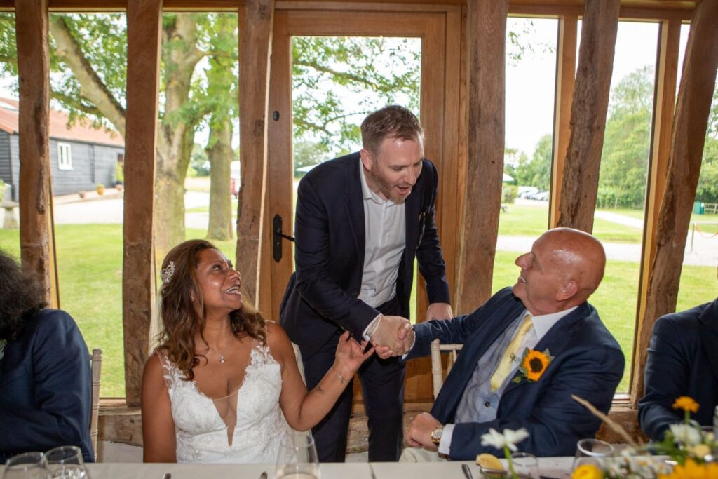 Bride and groom shaking hands with wedding magician after a trick at the top table