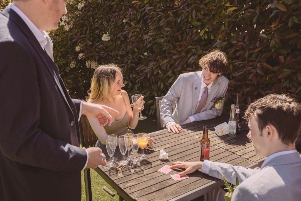 Wedding magician performing table magic for guests outside in the sunshine