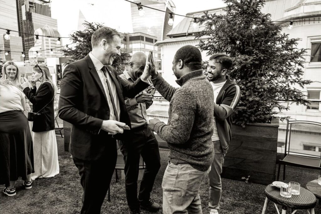 Guests high-fiving after magic trick at office Christmas party