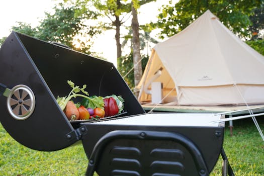 A barbecue grill with fresh vegetables beside a camping tent outdoors in a sunny setting.