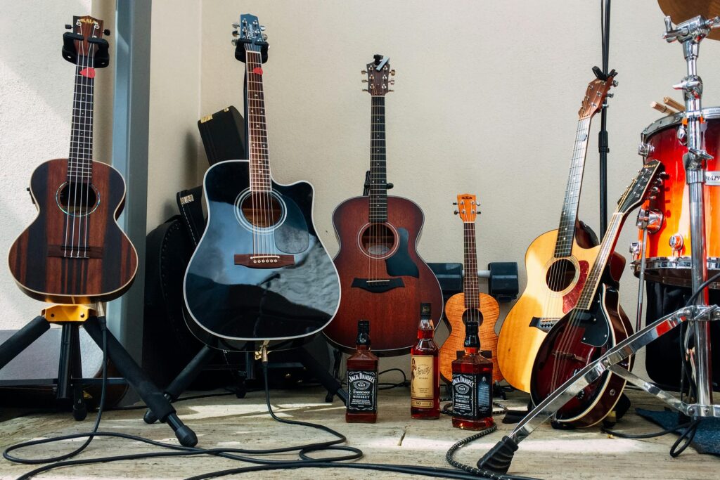 Collection of acoustic guitars and Jack Daniels bottles in a music setup.