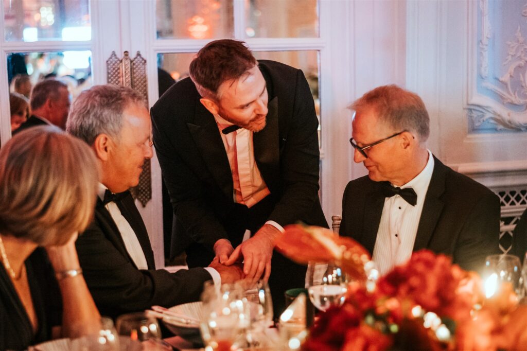 Corporate guests seated at table watching close-up magic performance