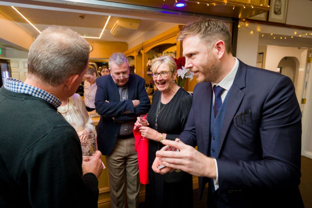 Magician in the clubroom at Braintree Golf Club with guests during a christmas party performing close up magic card trick